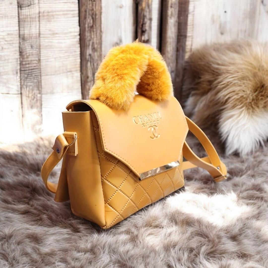 Side view of luxury quilted women's handbag with faux fur handle and adjustable shoulder strap.
